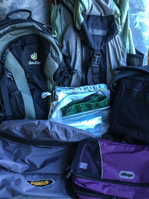 Bags, bags, bags! Clockwise from the top: my backpack, travel purse, clothing organizer eBags, dry bag, and daypack. In the middle: an assortment of resealable plastic bags and lightweight gear bags.