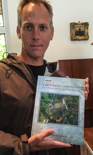 Chris holding the book Dr. Lynch wrote - available for sale on site at Jerpoint Abbey