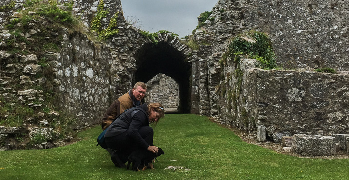 Dave and Lisa with our puppy friend in front of the covered cloister at Bridgetown Priory 