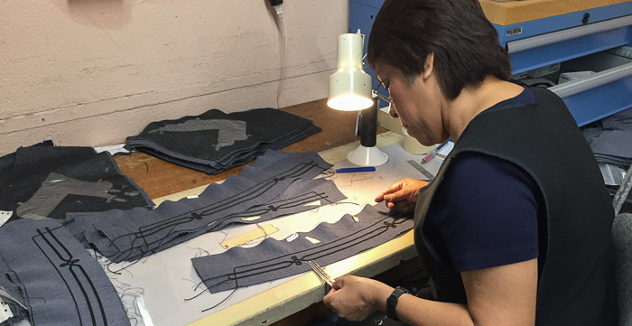 A uniform factory employee doing painstaking quality control work.
