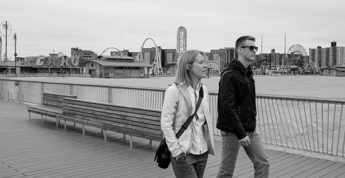 Julie and Matthew walking on the pier with Coney Island in the background.