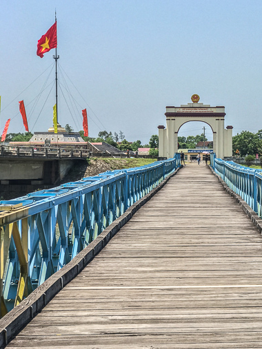 On the south side of the Hiền Lương Bridge looking north to the flagpole monument and museum. You can just barely see where the bridge paint transitions to yellow on the south half.