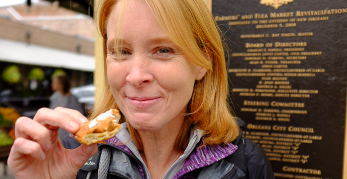 Julie showing off her praline-stuffed beignet from a stand in the French Market. Total sugar bomb!