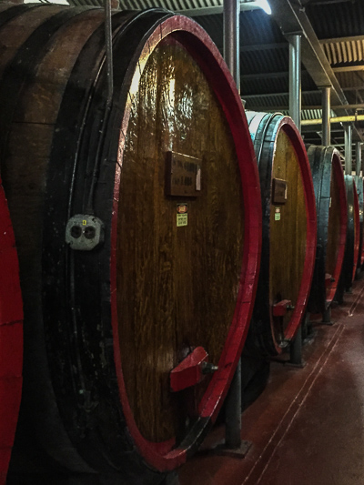 White oak wine barrels. To clean each barrel, men used to climb inside through a tiny door on the front (now blocked by the chunk of red-painted wood).